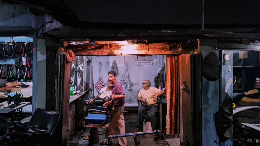 Two men in a dimly lit barbershop with a single warm overhead light